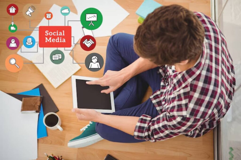 A person sitting on the floor using a tablet, surrounded by papers and coffee, with social media icons displayed above.