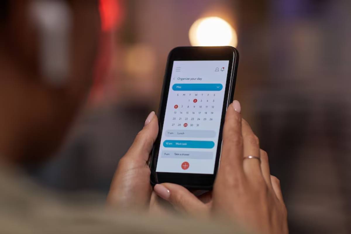 A person uses a smartphone to schedule their day, featuring a calendar with events like Lunch and Work task.