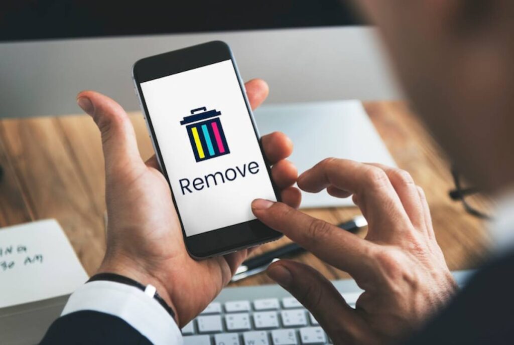 A person holding a smartphone displaying a Remove option with a colorful trash can icon, indicating file deletion.