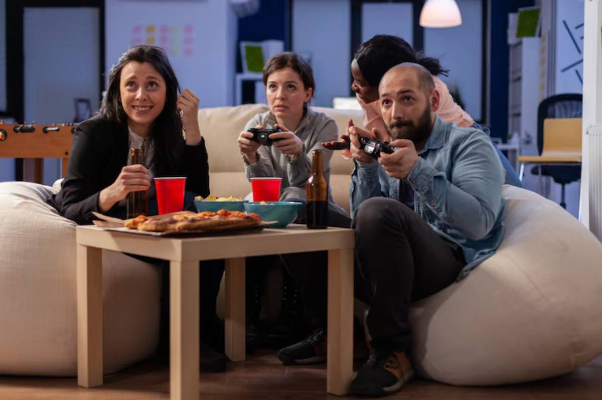 A group of friends enjoying a gaming night, sitting on bean bags with snacks, drinks, and game controllers on a coffee table.