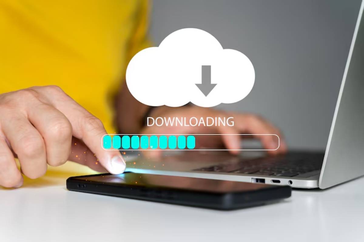 A person in a yellow shirt taps a smartphone as a download progress bar appears above, indicating a file transfer from a laptop.