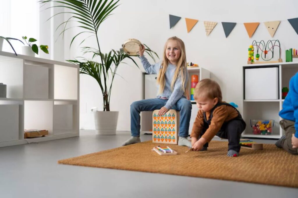 Children play in a bright room decorated with plants and toys, with one child holding a tambourine on a patterned box.