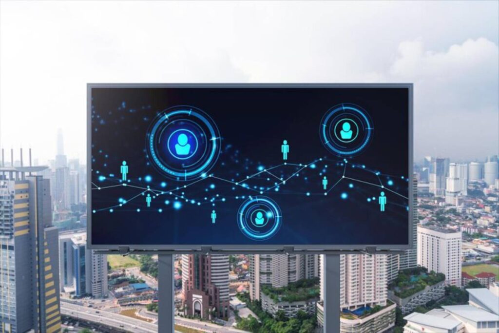 A digital billboard displays network icons representing people and connections against a city skyline background.
