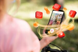A person holds a smartphone displaying a vibrant Instagram feed, surrounded by social media icons floating in a natural outdoor setting.